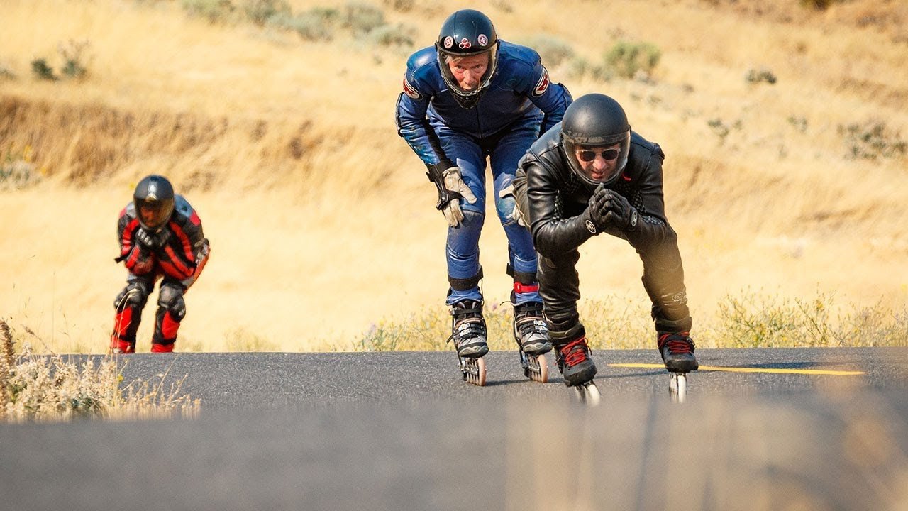 Vận động viên Downhill Skating đang trượt patin xuống dốc với tốc độ cao, trang bị đồ bảo hộ đầy đủ