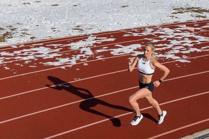 Vận động viên nữ chạy nước rút 100m với tốc độ cao trên đường đua điền kinh chuyên nghiệp